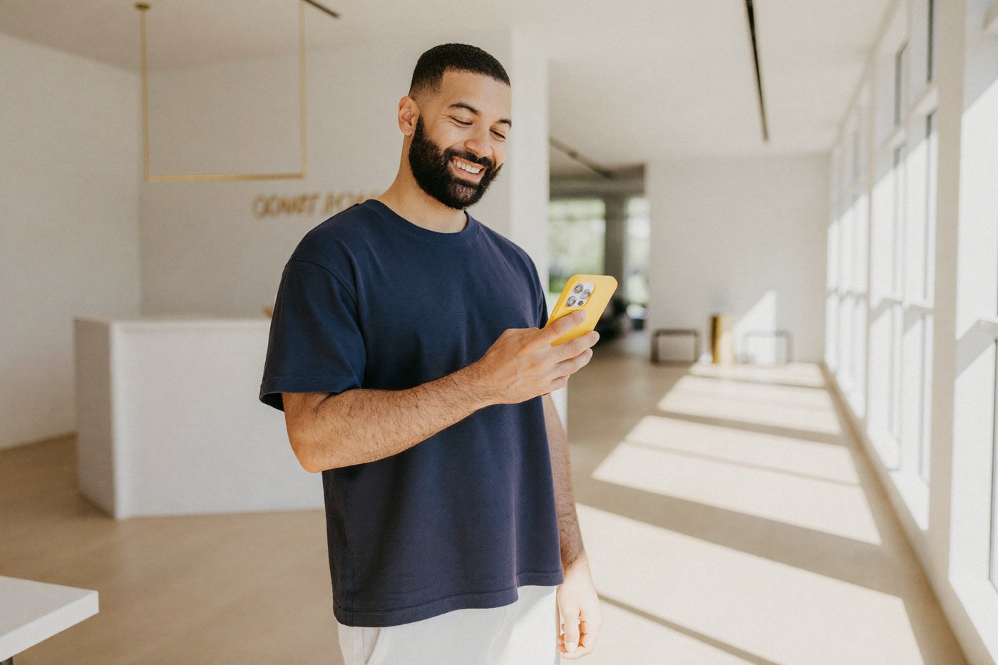 Dono de academia sorrindo ao ver o WhatsApp numa recepção clara